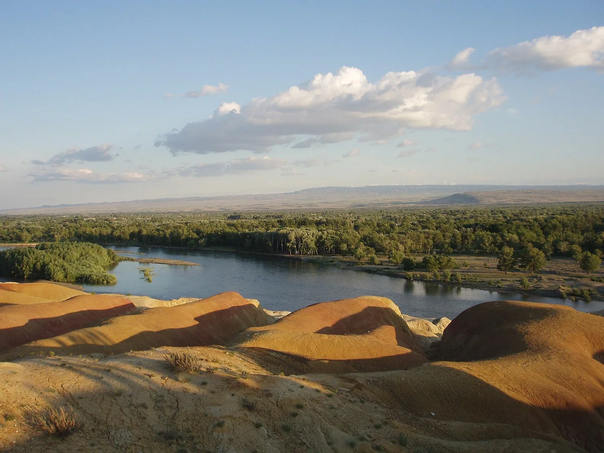 Warm-toned rock formations meet the Irtysh River oasis at Rainbow Beach.
