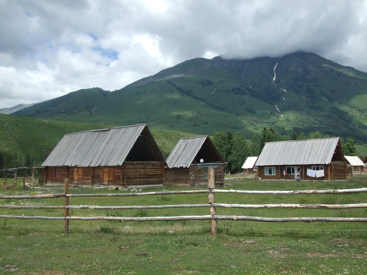 Timber houses and fences beneath Hemu’s green hills.