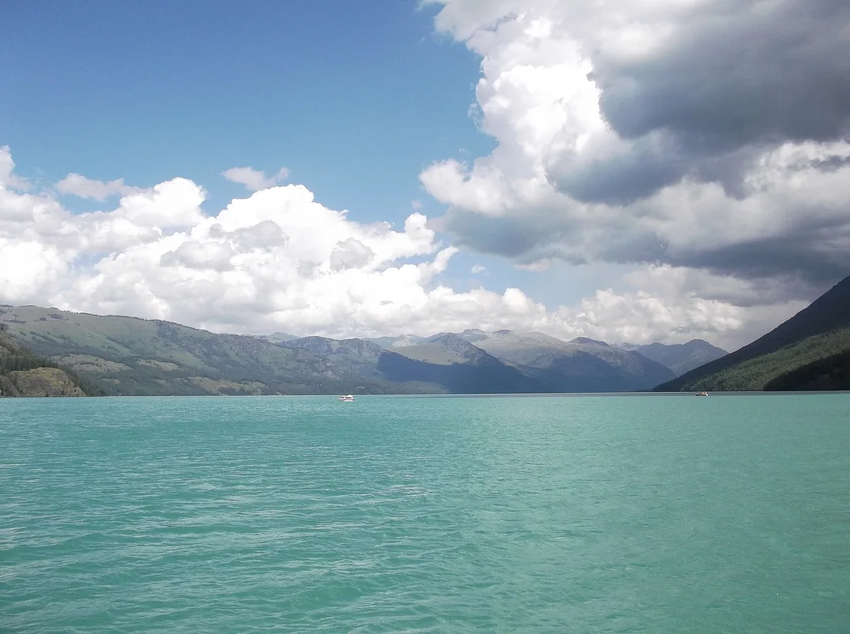 Clouds and distant ridges frame the open waters of Kanas Lake.