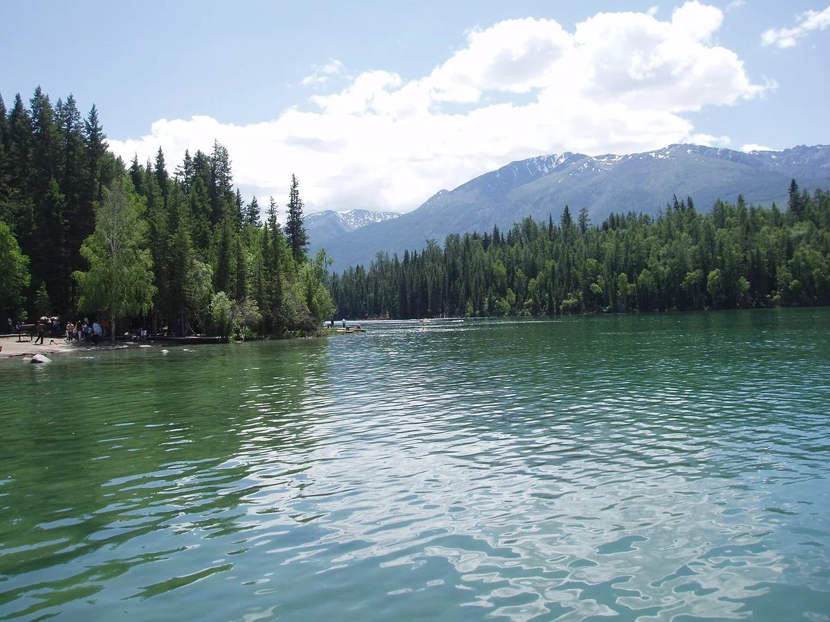 A closer lakeside view of Kanas, with clear water and forest reflections.