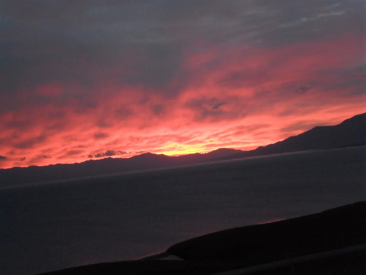 A photographed sunrise over Sayram Lake’s distant mountains.