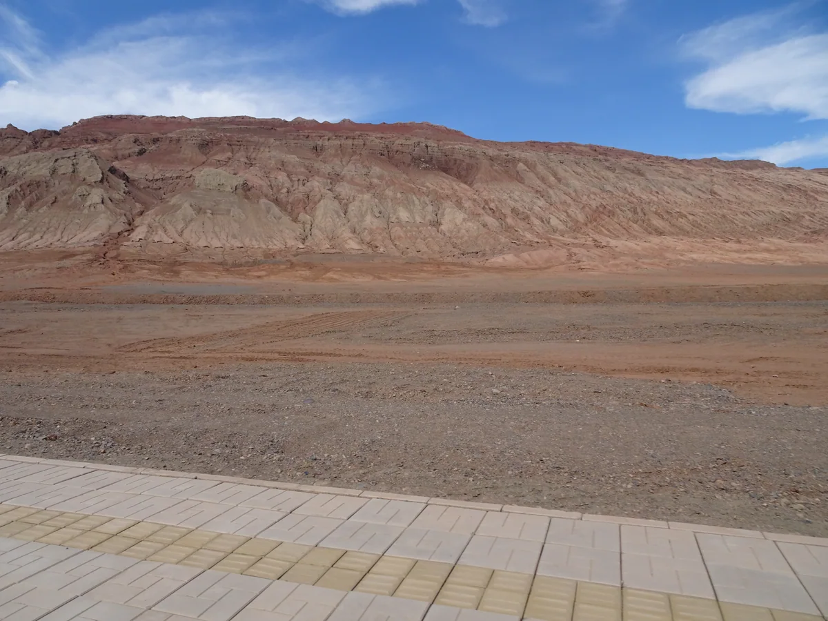 A broad red-brown ridge of the Flaming Mountains beneath a blue sky.
